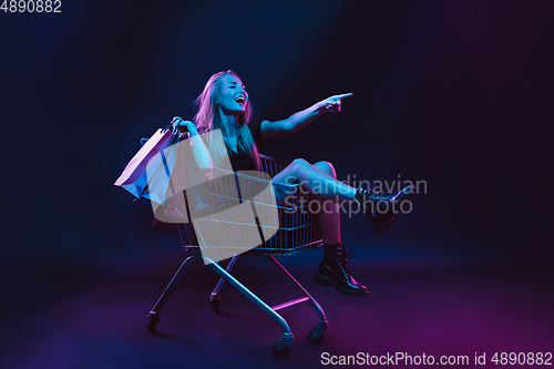 Image of Portrait of young woman in neon light on dark backgound. The human emotions, black friday, cyber monday, purchases, sales, finance concept.