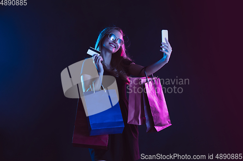 Image of Portrait of young woman in neon light on dark backgound. The human emotions, black friday, cyber monday, purchases, sales, finance concept.