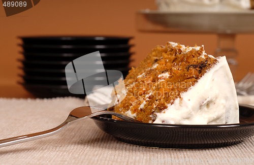 Image of Piece of carrot cake with plates in background