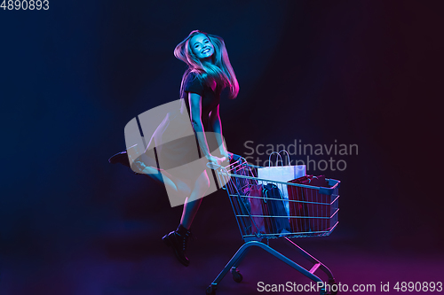 Image of Portrait of young woman in neon light on dark backgound. The human emotions, black friday, cyber monday, purchases, sales, finance concept.