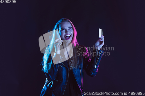 Image of Portrait of young woman in neon light on dark backgound. The human emotions, black friday, cyber monday, purchases, sales, finance concept.