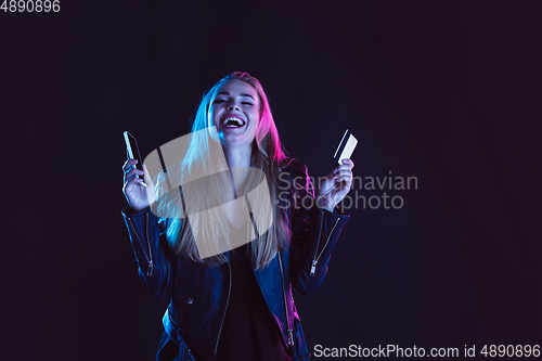 Image of Portrait of young woman in neon light on dark backgound. The human emotions, black friday, cyber monday, purchases, sales, finance concept.