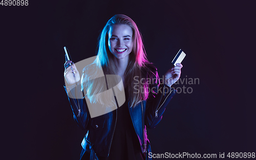 Image of Portrait of young woman in neon light on dark backgound. The human emotions, black friday, cyber monday, purchases, sales, finance concept.