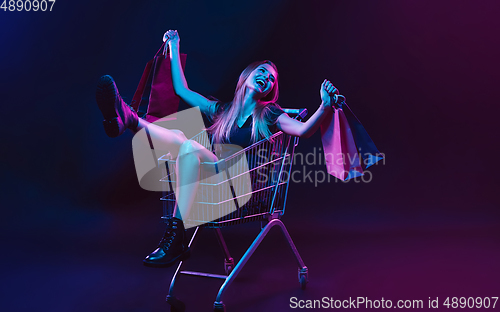 Image of Portrait of young woman in neon light on dark backgound. The human emotions, black friday, cyber monday, purchases, sales, finance concept.