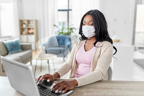 Image of woman in mask with laptop working at home office