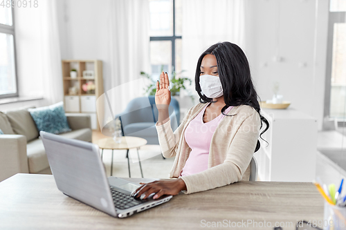 Image of woman in mask with laptop having video call