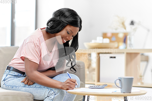 Image of african woman with papers and calculator at home