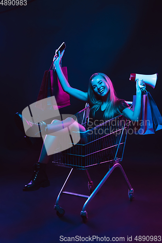 Image of Portrait of young woman in neon light on dark backgound. The human emotions, black friday, cyber monday, purchases, sales, finance concept.