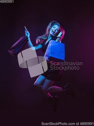 Image of Portrait of young woman in neon light on dark backgound. The human emotions, black friday, cyber monday, purchases, sales, finance concept.