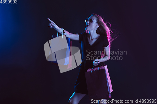 Image of Portrait of young woman in neon light on dark backgound. The human emotions, black friday, cyber monday, purchases, sales, finance concept.