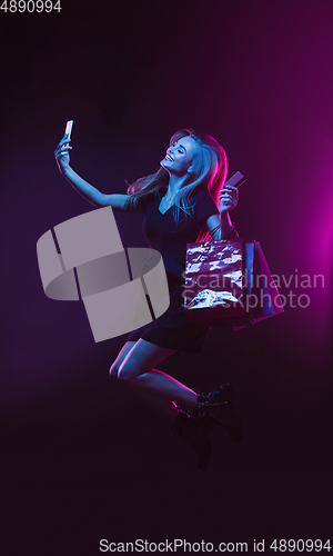 Image of Portrait of young woman in neon light on dark backgound. The human emotions, black friday, cyber monday, purchases, sales, finance concept.