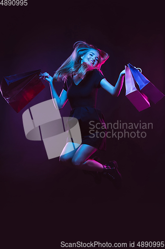 Image of Portrait of young woman in neon light on dark backgound. The human emotions, black friday, cyber monday, purchases, sales, finance concept.