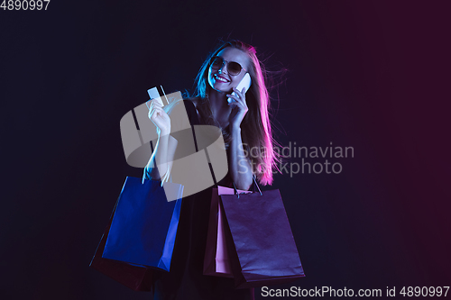 Image of Portrait of young woman in neon light on dark backgound. The human emotions, black friday, cyber monday, purchases, sales, finance concept.