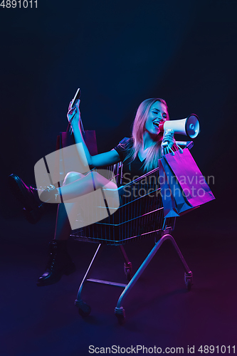 Image of Portrait of young woman in neon light on dark backgound. The human emotions, black friday, cyber monday, purchases, sales, finance concept.