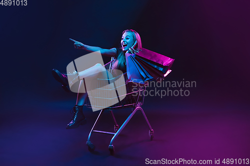 Image of Portrait of young woman in neon light on dark backgound. The human emotions, black friday, cyber monday, purchases, sales, finance concept.