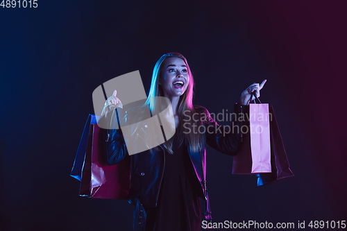 Image of Portrait of young woman in neon light on dark backgound. The human emotions, black friday, cyber monday, purchases, sales, finance concept.