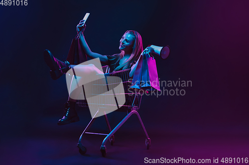 Image of Portrait of young woman in neon light on dark backgound. The human emotions, black friday, cyber monday, purchases, sales, finance concept.