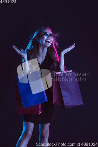 Image of Portrait of young woman in neon light on dark backgound. The human emotions, black friday, cyber monday, purchases, sales, finance concept.