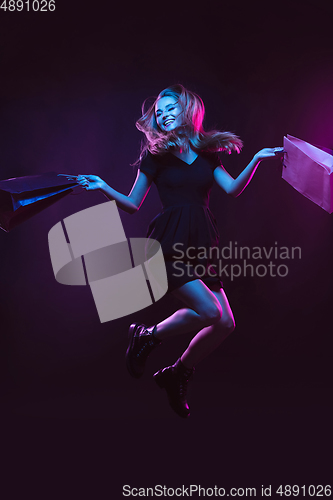 Image of Portrait of young woman in neon light on dark backgound. The human emotions, black friday, cyber monday, purchases, sales, finance concept.