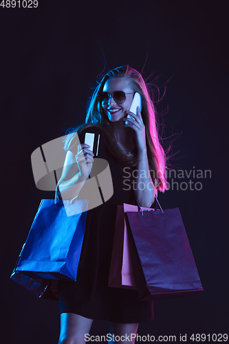 Image of Portrait of young woman in neon light on dark backgound. The human emotions, black friday, cyber monday, purchases, sales, finance concept.