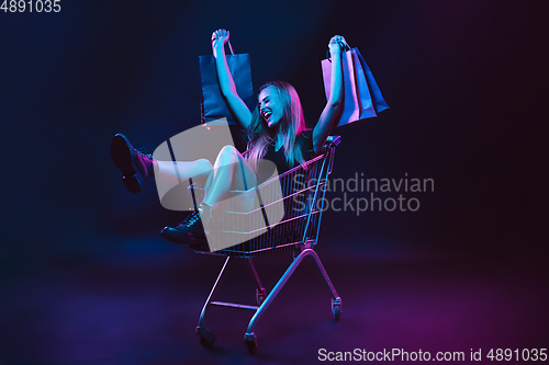 Image of Portrait of young woman in neon light on dark backgound. The human emotions, black friday, cyber monday, purchases, sales, finance concept.