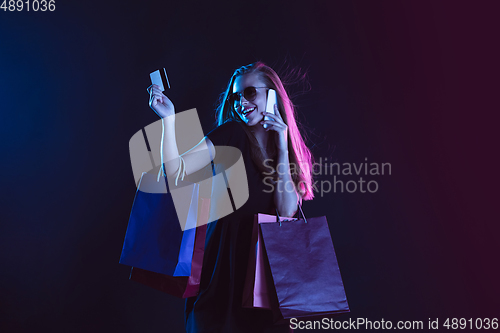 Image of Portrait of young woman in neon light on dark backgound. The human emotions, black friday, cyber monday, purchases, sales, finance concept.