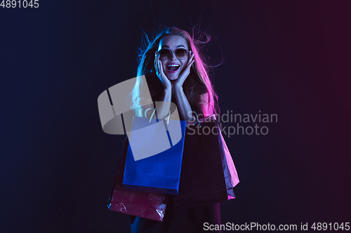 Image of Portrait of young woman in neon light on dark backgound. The human emotions, black friday, cyber monday, purchases, sales, finance concept.