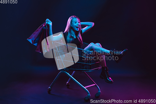 Image of Portrait of young woman in neon light on dark backgound. The human emotions, black friday, cyber monday, purchases, sales, finance concept.