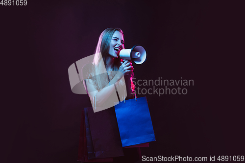 Image of Portrait of young woman in neon light on dark backgound. The human emotions, black friday, cyber monday, purchases, sales, finance concept.