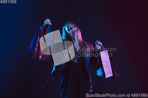 Image of Portrait of young woman in neon light on dark backgound. The human emotions, black friday, cyber monday, purchases, sales, finance concept.