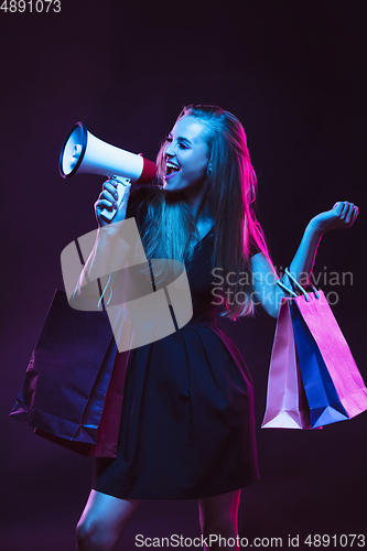 Image of Portrait of young woman in neon light on dark backgound. The human emotions, black friday, cyber monday, purchases, sales, finance concept.