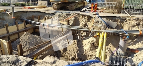 Image of The process of laying of engineering and heating systems. Many multicolored plastic pipes are in a trench of sand in perspective