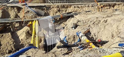 Image of The process of laying of engineering and heating systems. Many multicolored plastic pipes are in a trench of sand in perspective