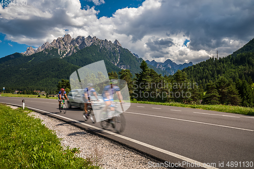 Image of Cyclists riding a bicycle on the road in the background the Dolo