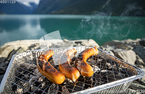 Image of Grilling sausages on disposable barbecue grid.