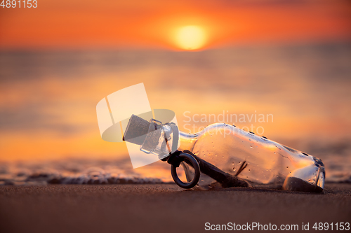 Image of Message in the bottle against the Sun setting down