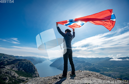 Image of Woman with a waving flag of Norway on the background of nature