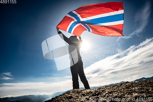 Image of Woman with a waving flag of Norway on the background of nature