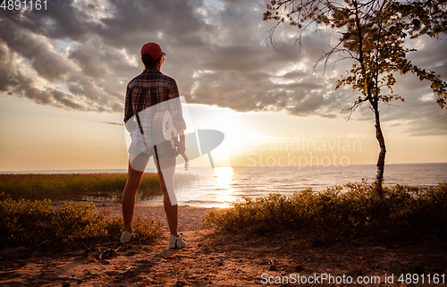 Image of Woman at sunset holding a ukulele