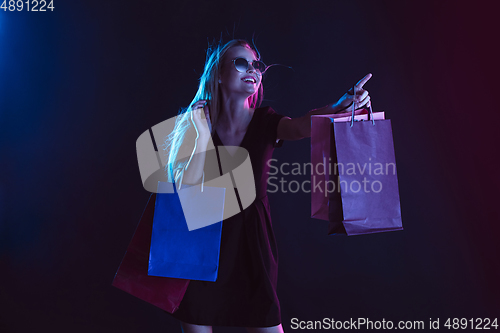 Image of Portrait of young woman in neon light on dark backgound. The human emotions, black friday, cyber monday, purchases, sales, finance concept.