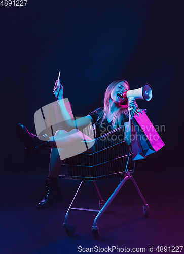 Image of Portrait of young woman in neon light on dark backgound. The human emotions, black friday, cyber monday, purchases, sales, finance concept.