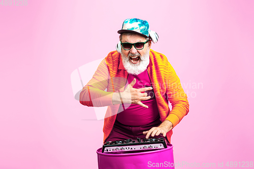 Image of Senior hipster man wearing eyeglasses posing on pink background. Tech and joyful elderly lifestyle concept