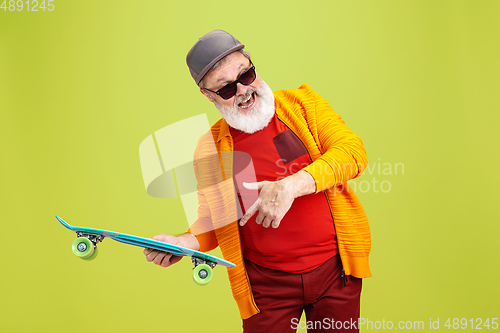 Image of Senior hipster man wearing eyeglasses posing on green background. Tech and joyful elderly lifestyle concept