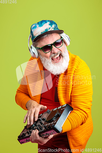 Image of Senior hipster man wearing eyeglasses posing on green background. Tech and joyful elderly lifestyle concept