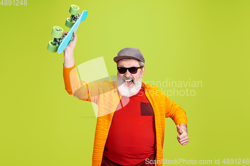 Image of Senior hipster man wearing eyeglasses posing on green background. Tech and joyful elderly lifestyle concept