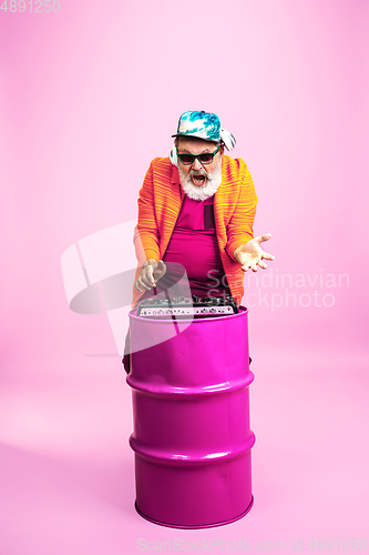 Image of Senior hipster man wearing eyeglasses posing on pink background. Tech and joyful elderly lifestyle concept