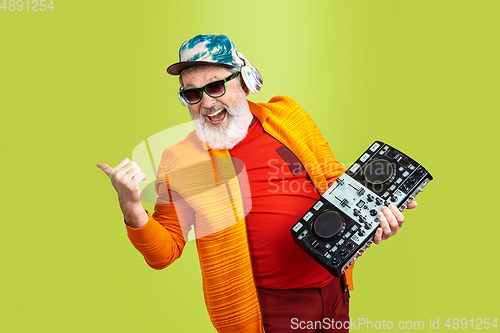 Image of Senior hipster man wearing eyeglasses posing on green background. Tech and joyful elderly lifestyle concept