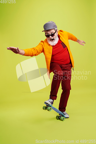 Image of Senior hipster man wearing eyeglasses posing on green background. Tech and joyful elderly lifestyle concept