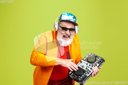 Image of Senior hipster man wearing eyeglasses posing on green background. Tech and joyful elderly lifestyle concept