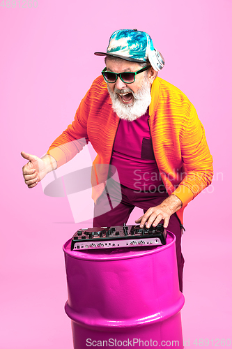 Image of Senior hipster man wearing eyeglasses posing on pink background. Tech and joyful elderly lifestyle concept